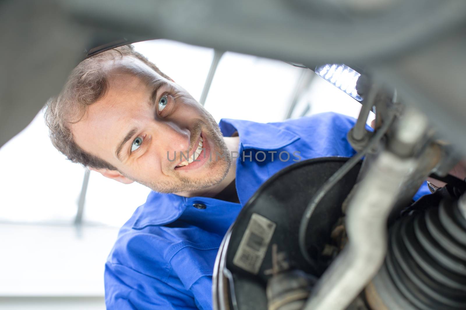 Car mechanic repairs the brakes of an automobile on a hydraulic lift