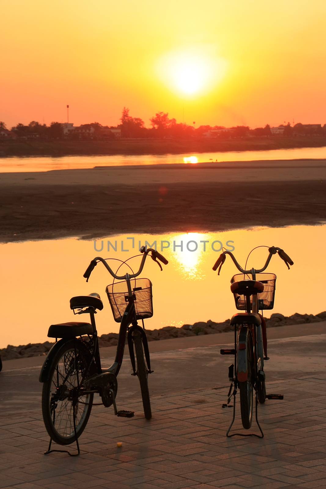 Silhouetted bicycles near Mekong river at sunset, Vientiane, Lao by donya_nedomam