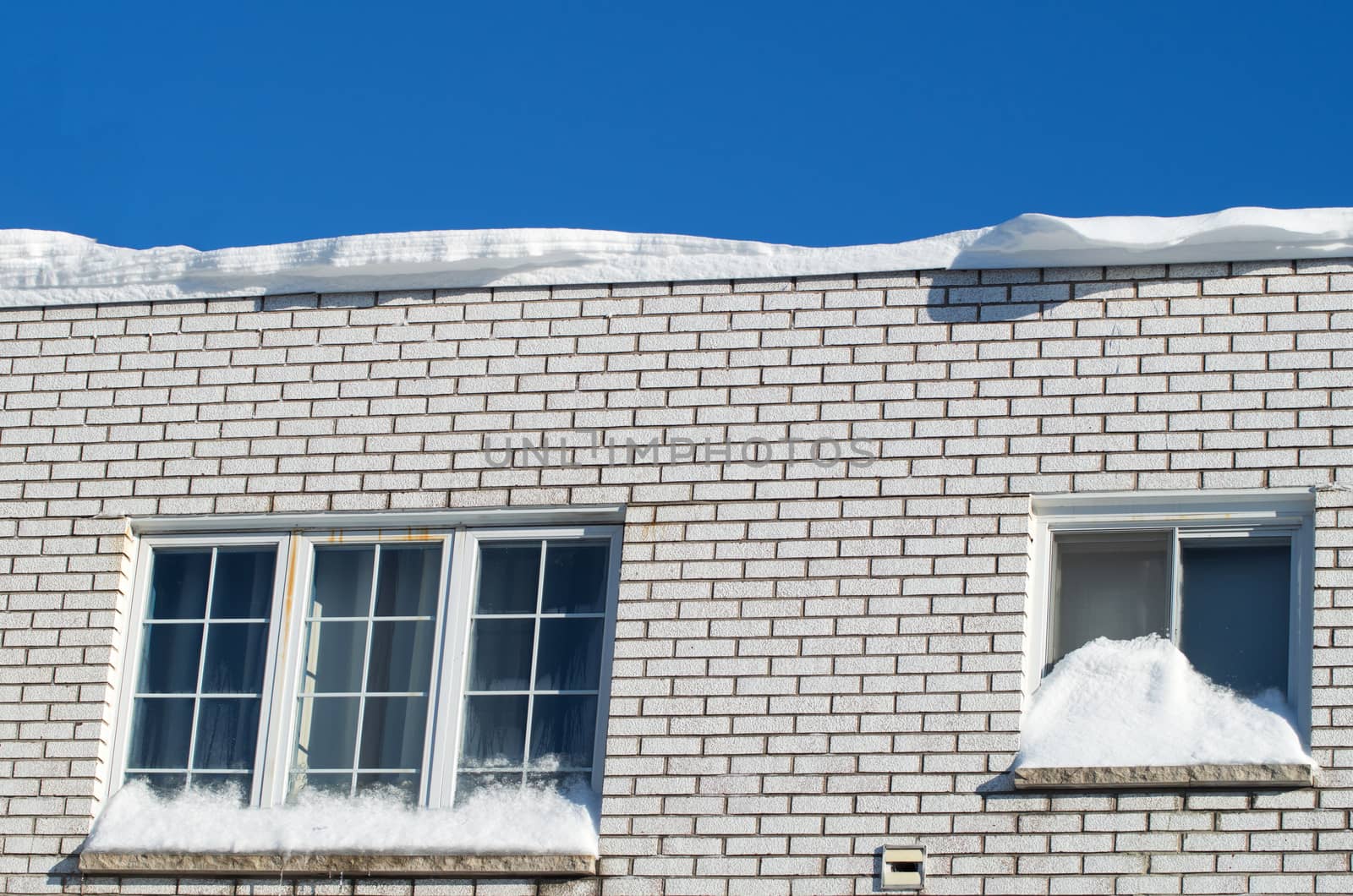 House with snow on roof and window during a sunny day in winter