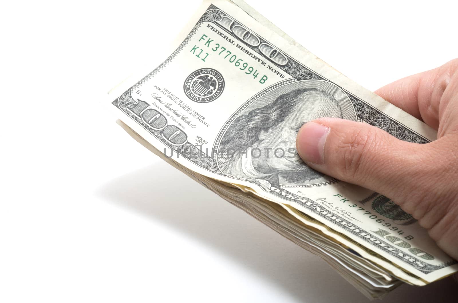 Hand holding a series of banknotes with 100 dollars on top on white background