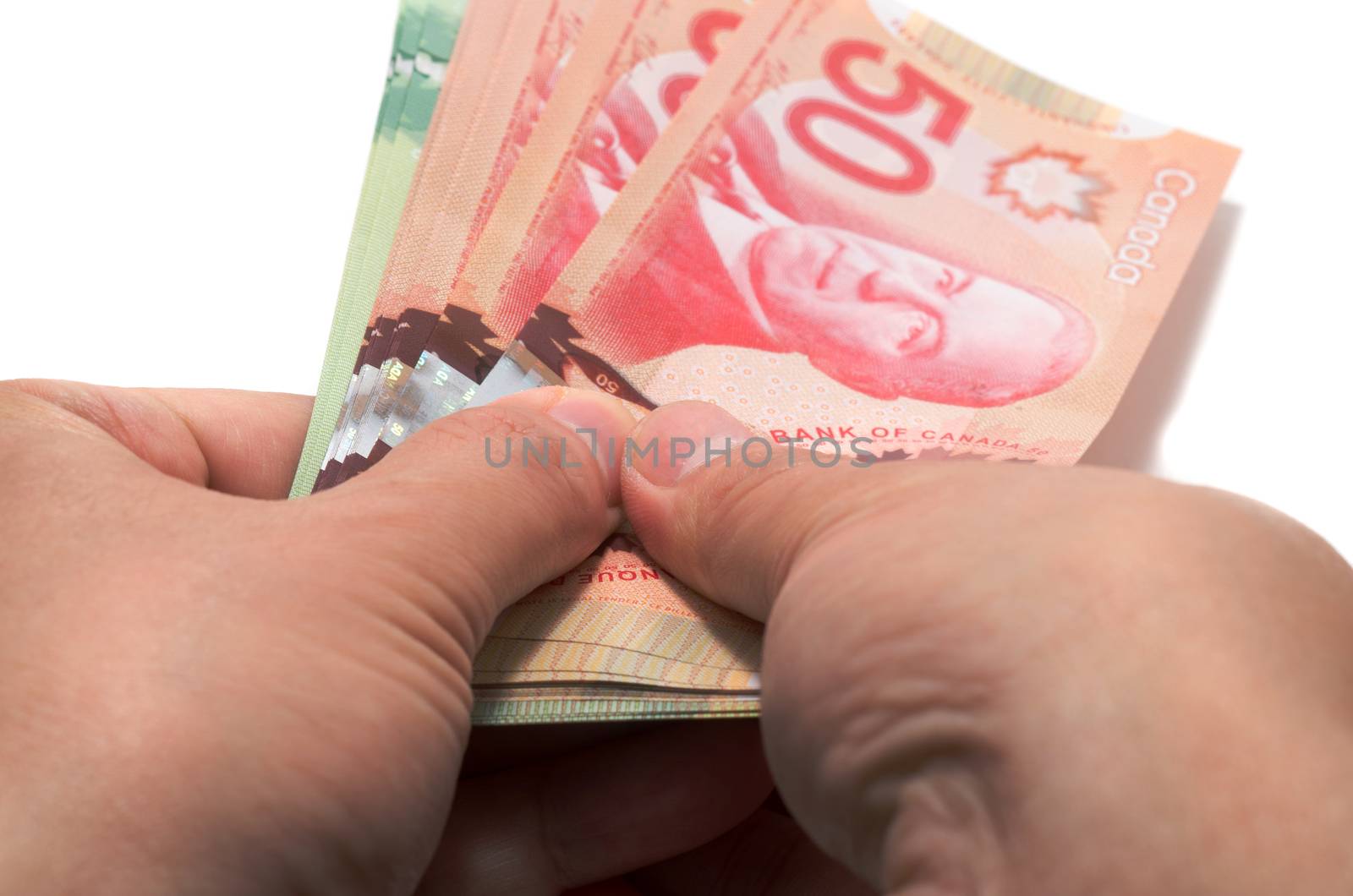 Hand holding a series of Canadian banknotes on white background