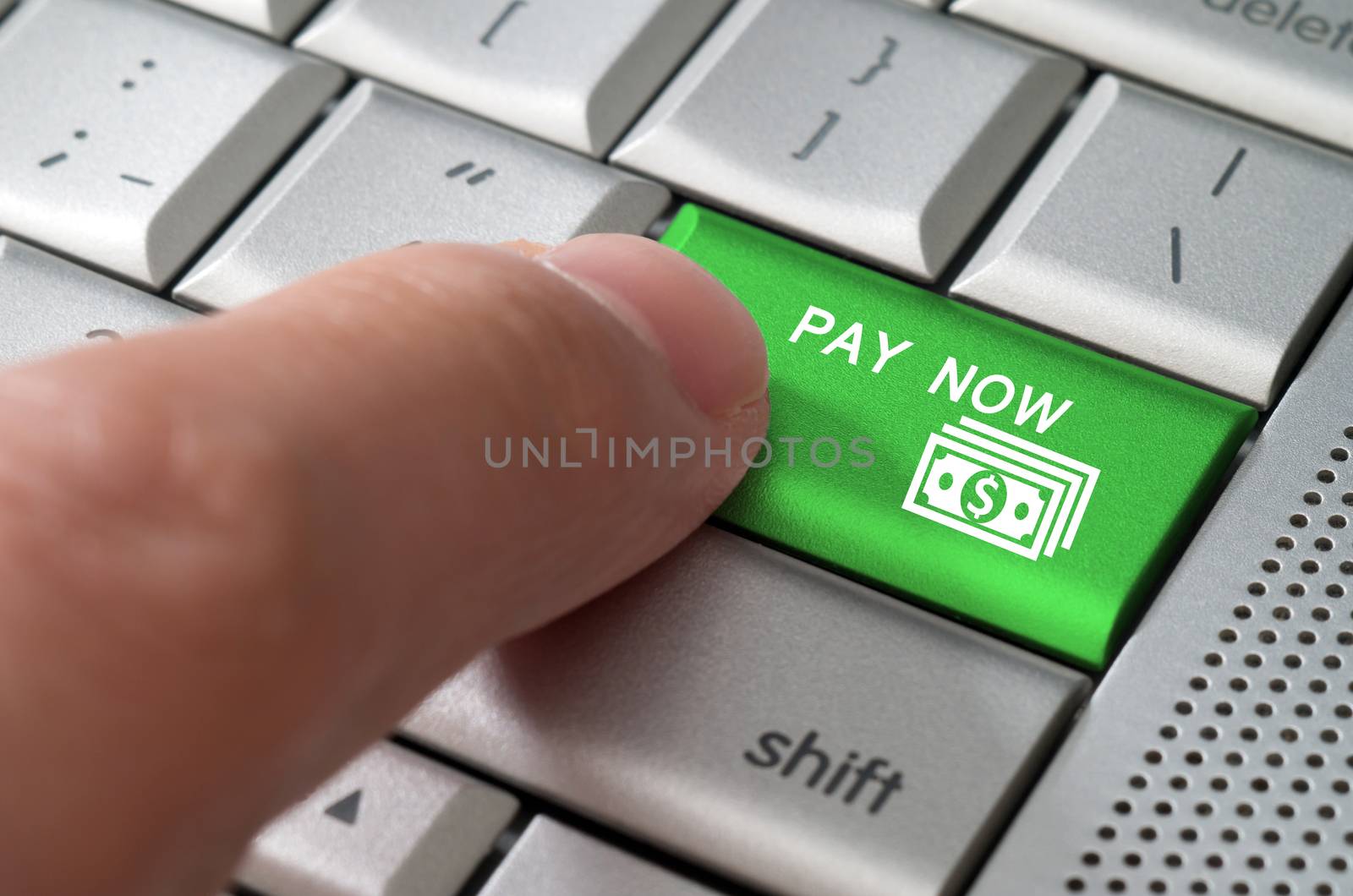 Business concept male finger pointing pay now key on  a metallic keyboard