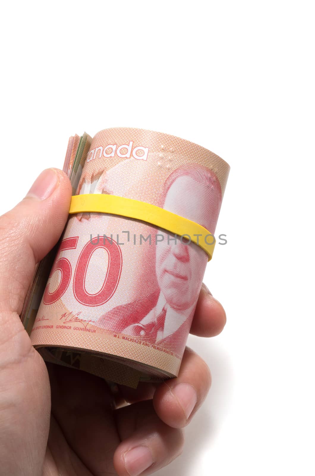 Hand holding a roll of 50 dollars Canadian with yellow plastic b by daoleduc