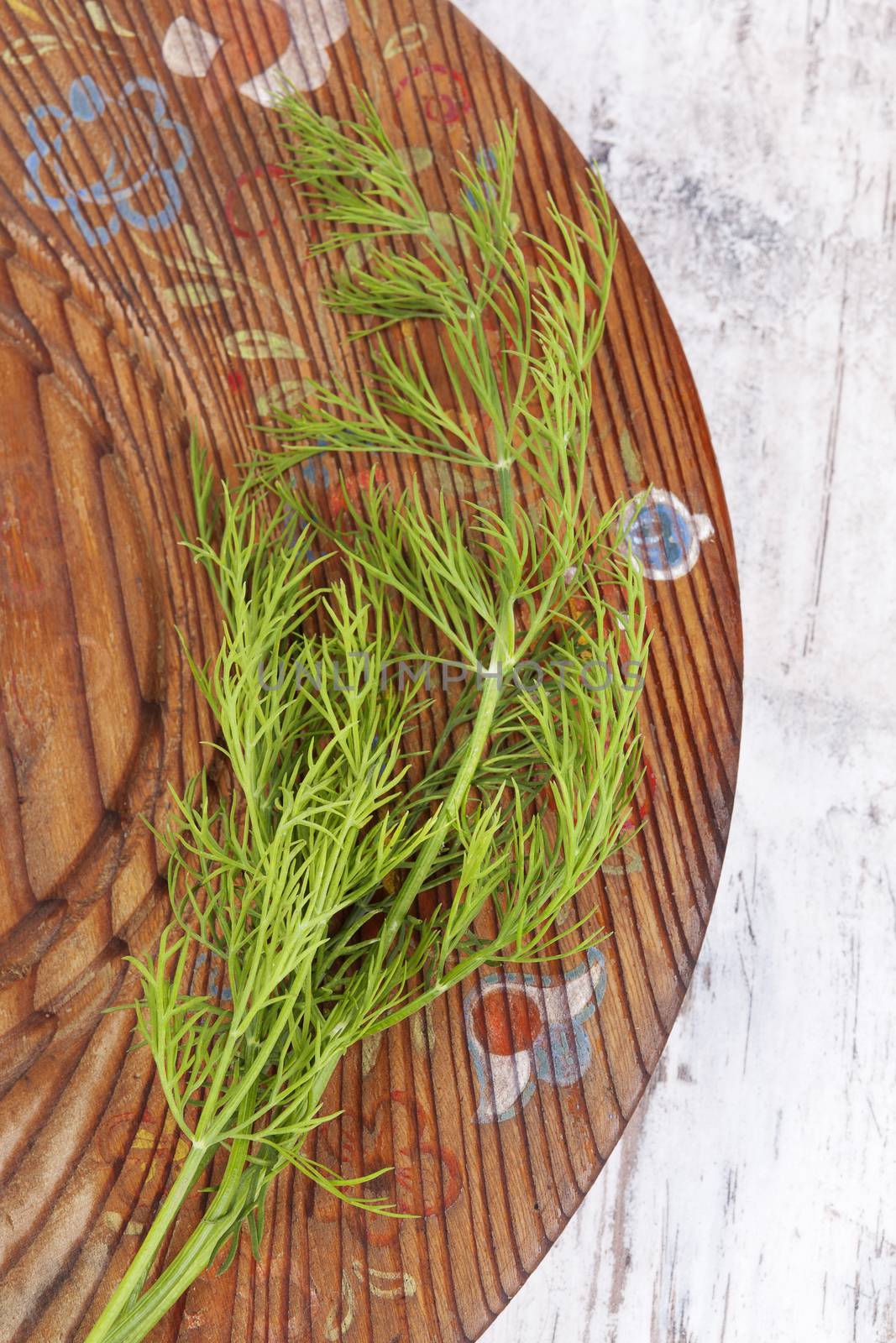 Fresh dill on wooden vintage plate, top view. Culinary aromatic herbs. 