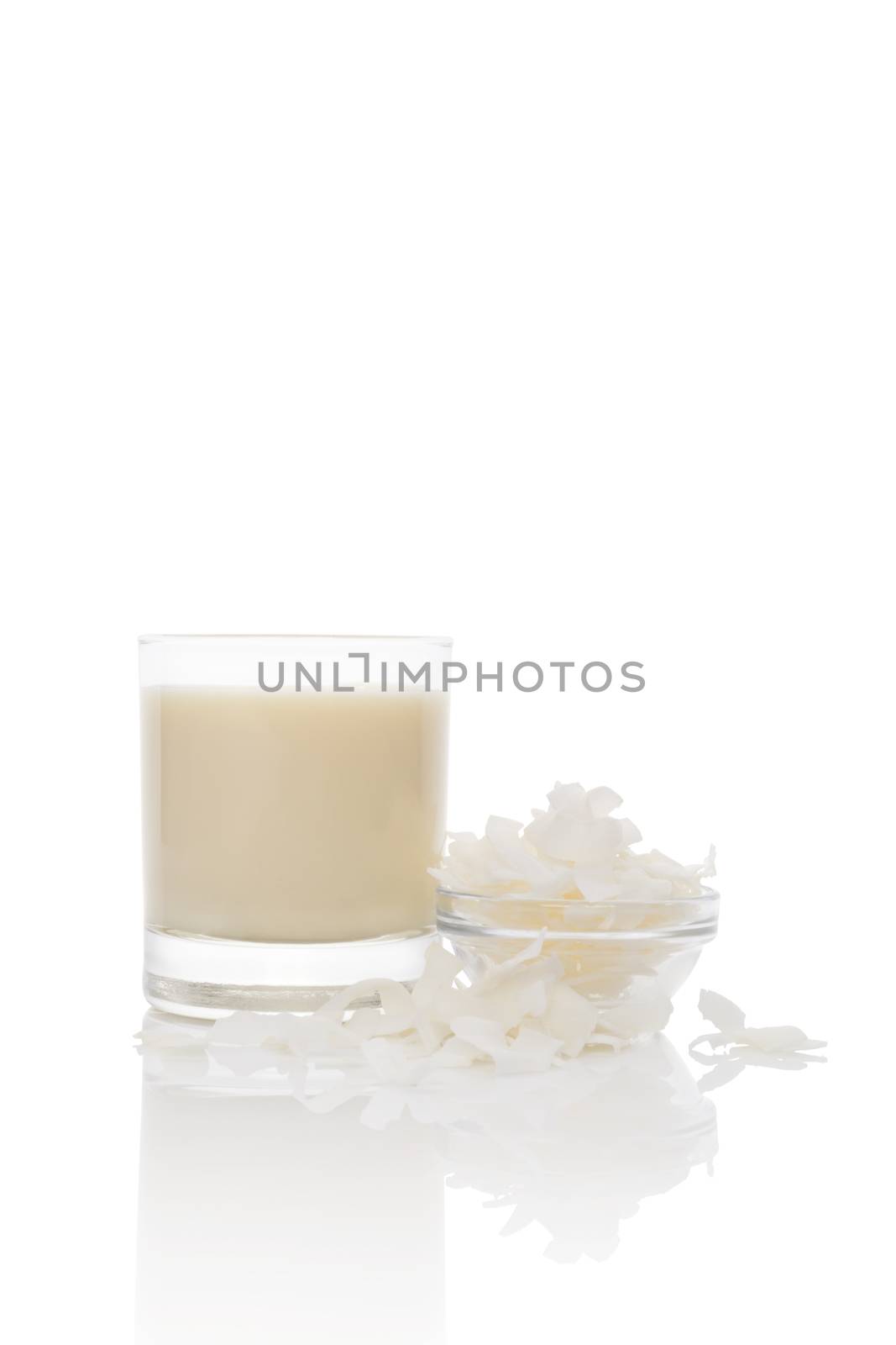 Coconut milk in glass, coconut flaked in bowl isolated on white background. Culinary healthy vegan and vegetarian eating.