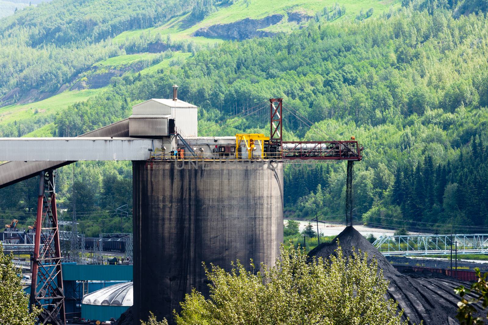 Black coal mine pile at coal fired power station in green valley