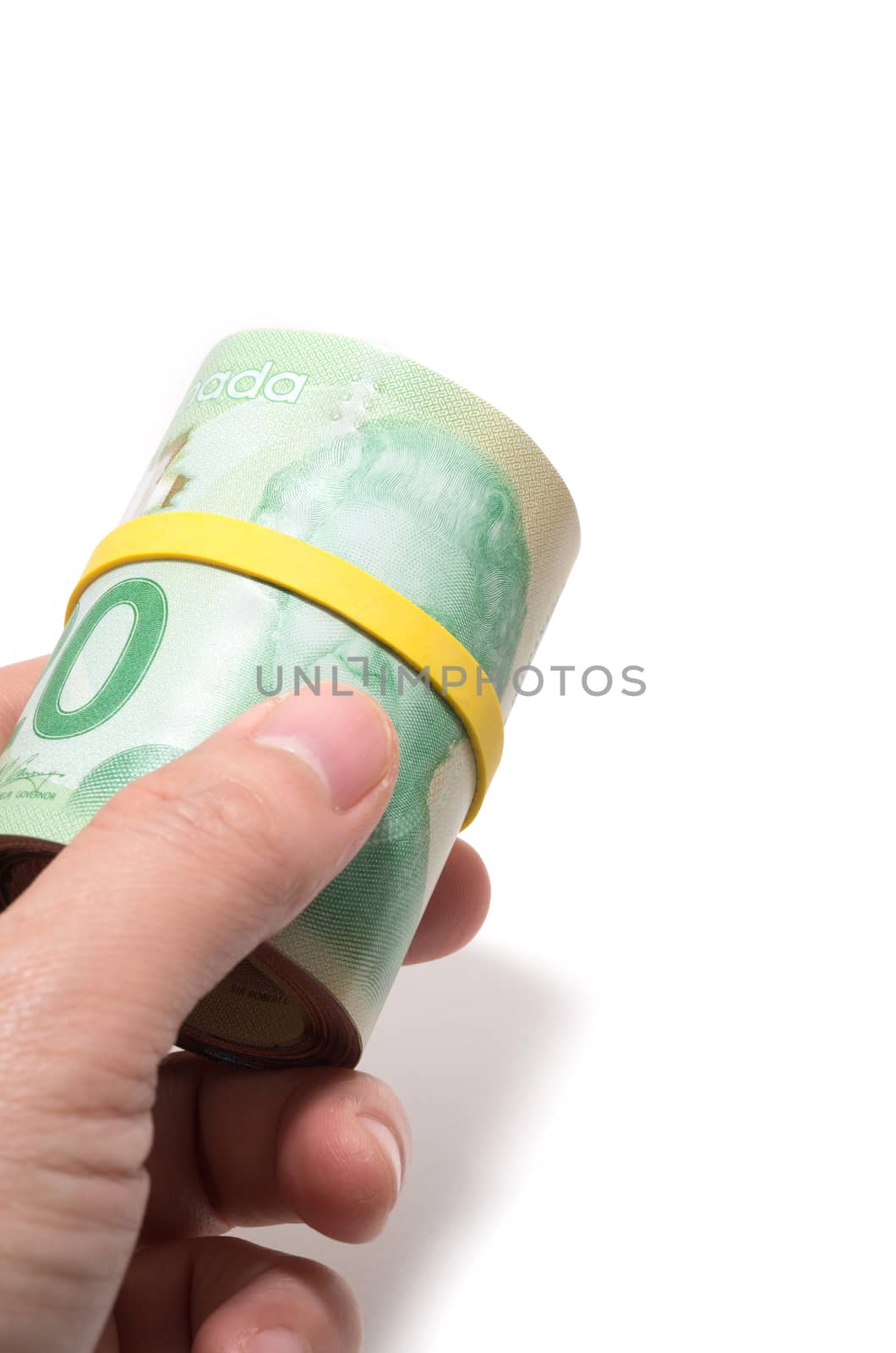 Hand holding a roll of 20 dollars Canadian with yellow plastic band over the eyes of the queen Elizabeth.