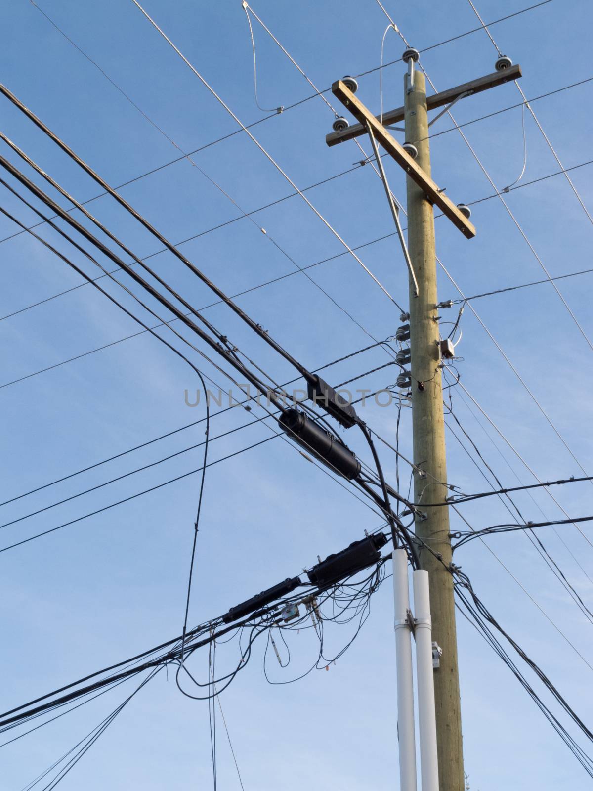 Utility pole hung with confusing and messed-up electricity power cables and telephone lines for residential supply