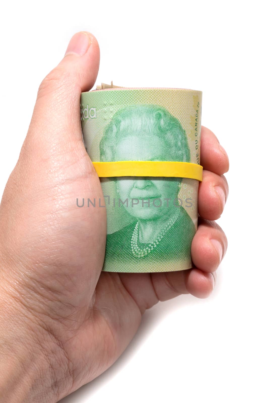 Hand holding a roll of 20 dollars Canadian with yellow plastic band over the eyes of the queen Elizabeth.