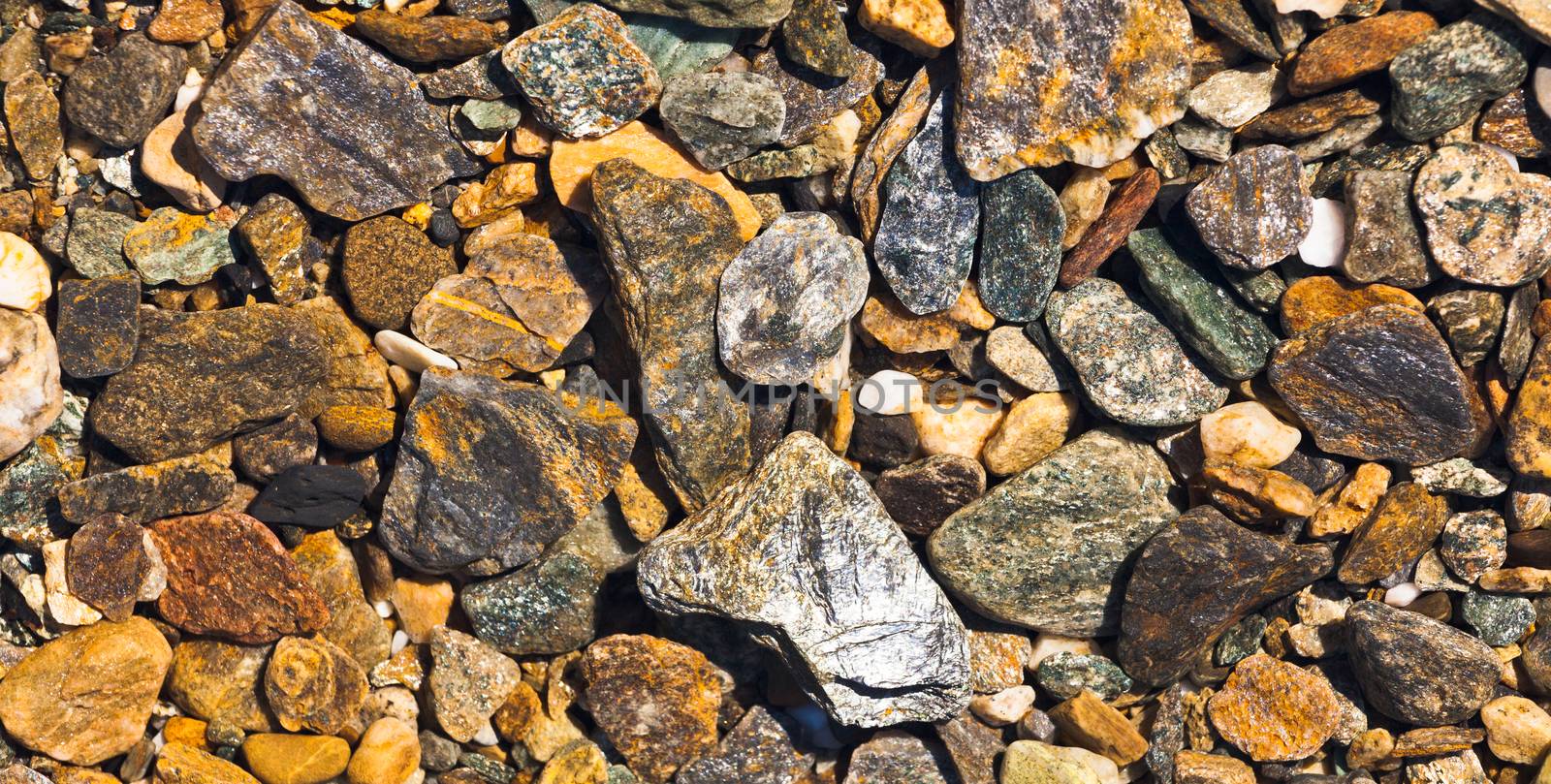 Deposit of rough shiny gravel nrown and grey as a geology nature background texture pattern