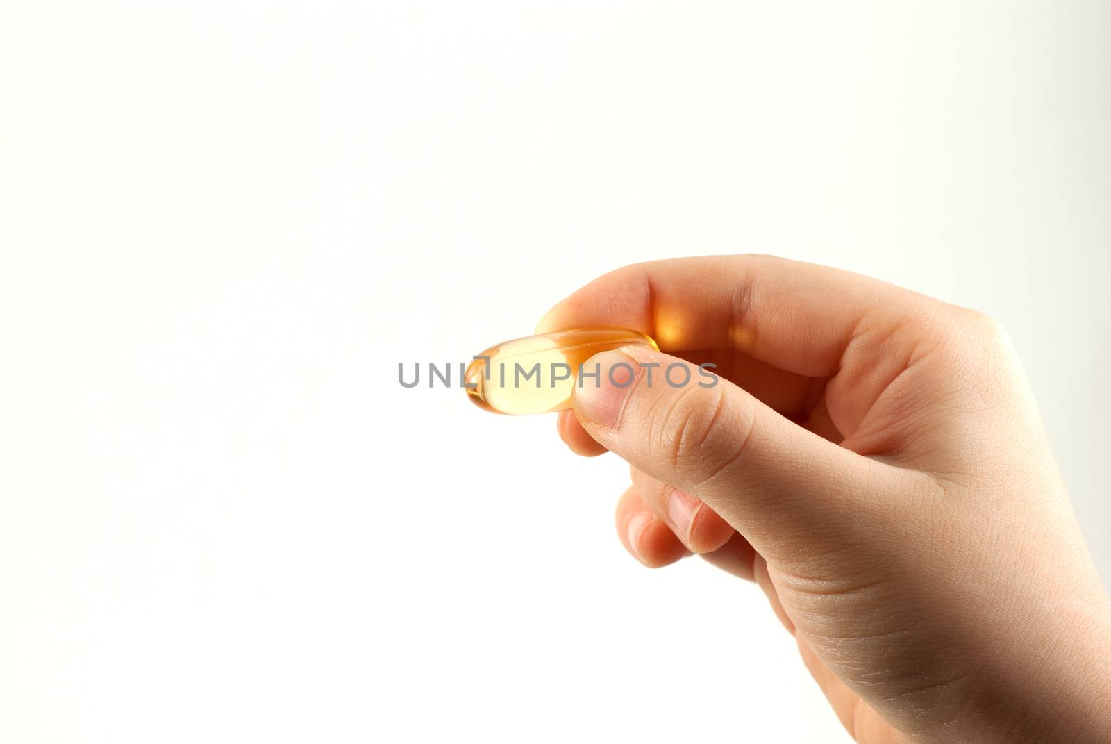 A hand from a child holding a fish oil capsule by daoleduc