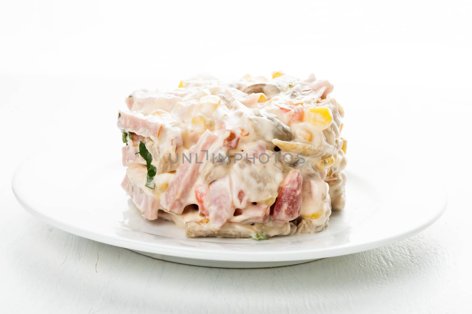 Portion of salad with ham, meat, mushrooms, vegetables and mayonnaise