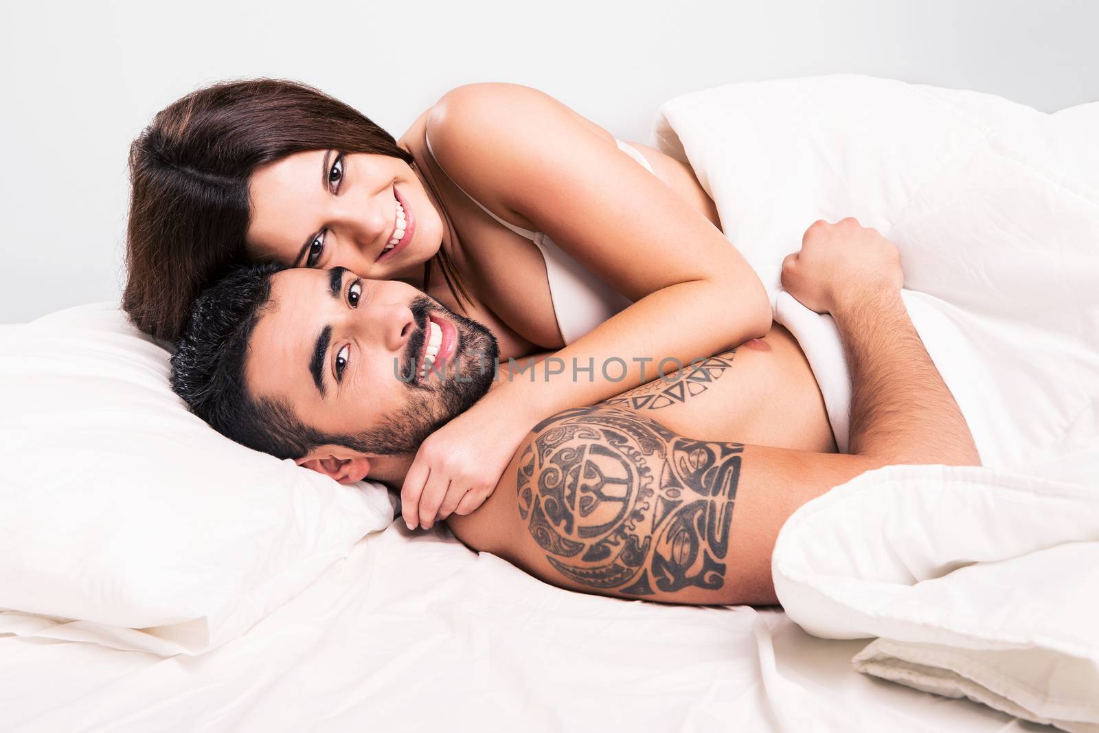 Love couple flirting and hugging in bed