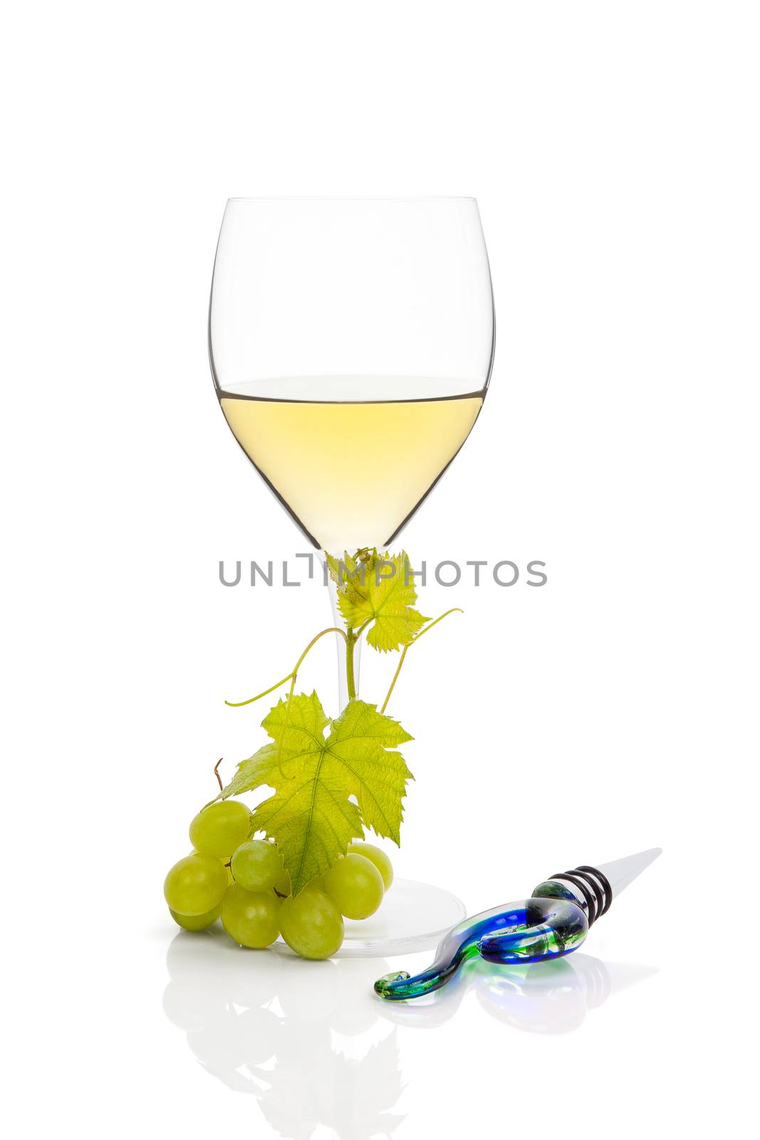 White wine in wine glass with green grapes and wine stopper isolated on white background. Luxurious wine still life.