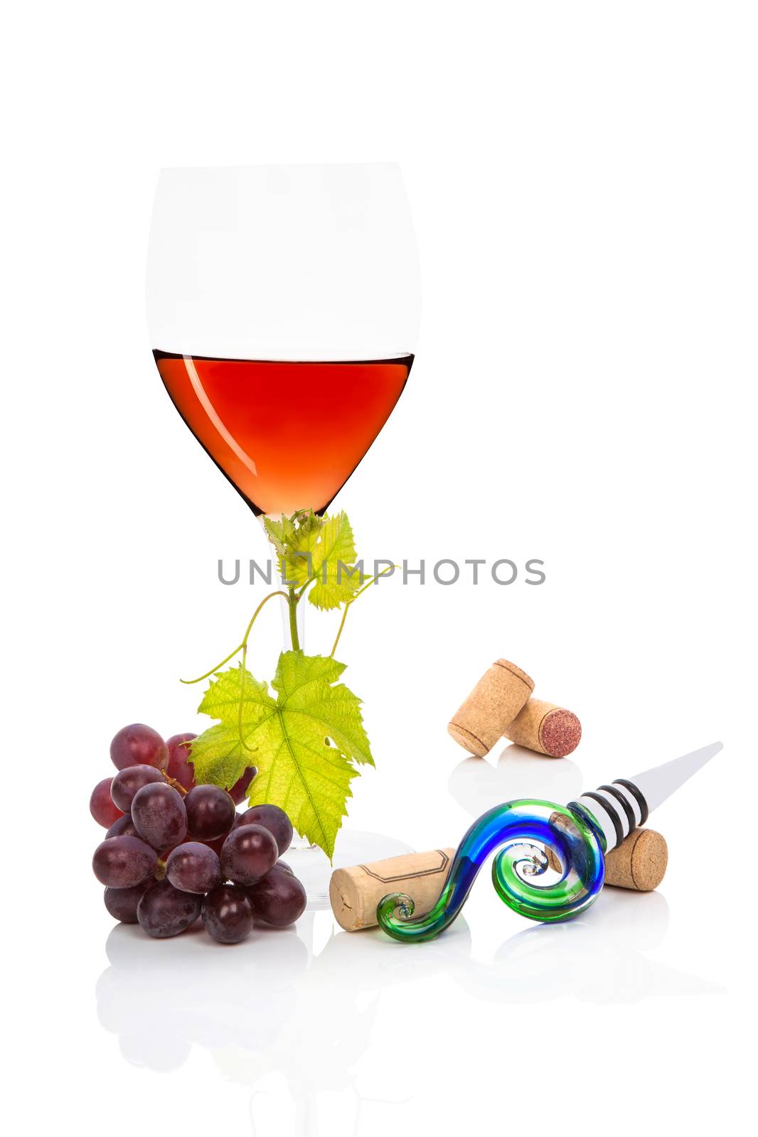Luxurious rose wine still life. Rose wine in wine glass, red grape, vine leaves, wine corks and wine stopper isolated on white background.
