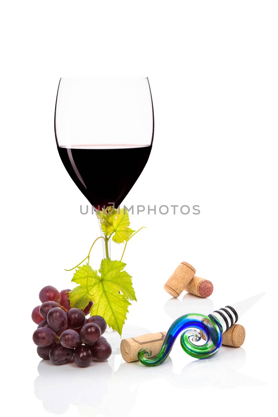 Red wine in wine glass, with cabernet sauvignon grapes, vine leaves wine stopper and wine corks isolated on white background. Culinary gourmet red wine drinking.
