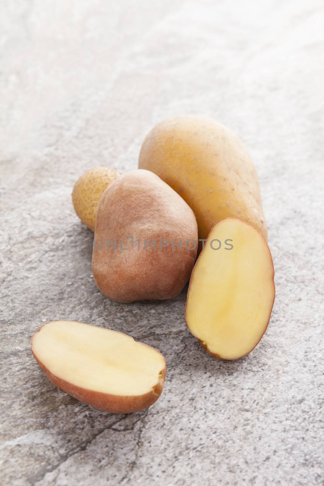 Raw yellow potatoes on natural stone background. Culinary vegetable eating.