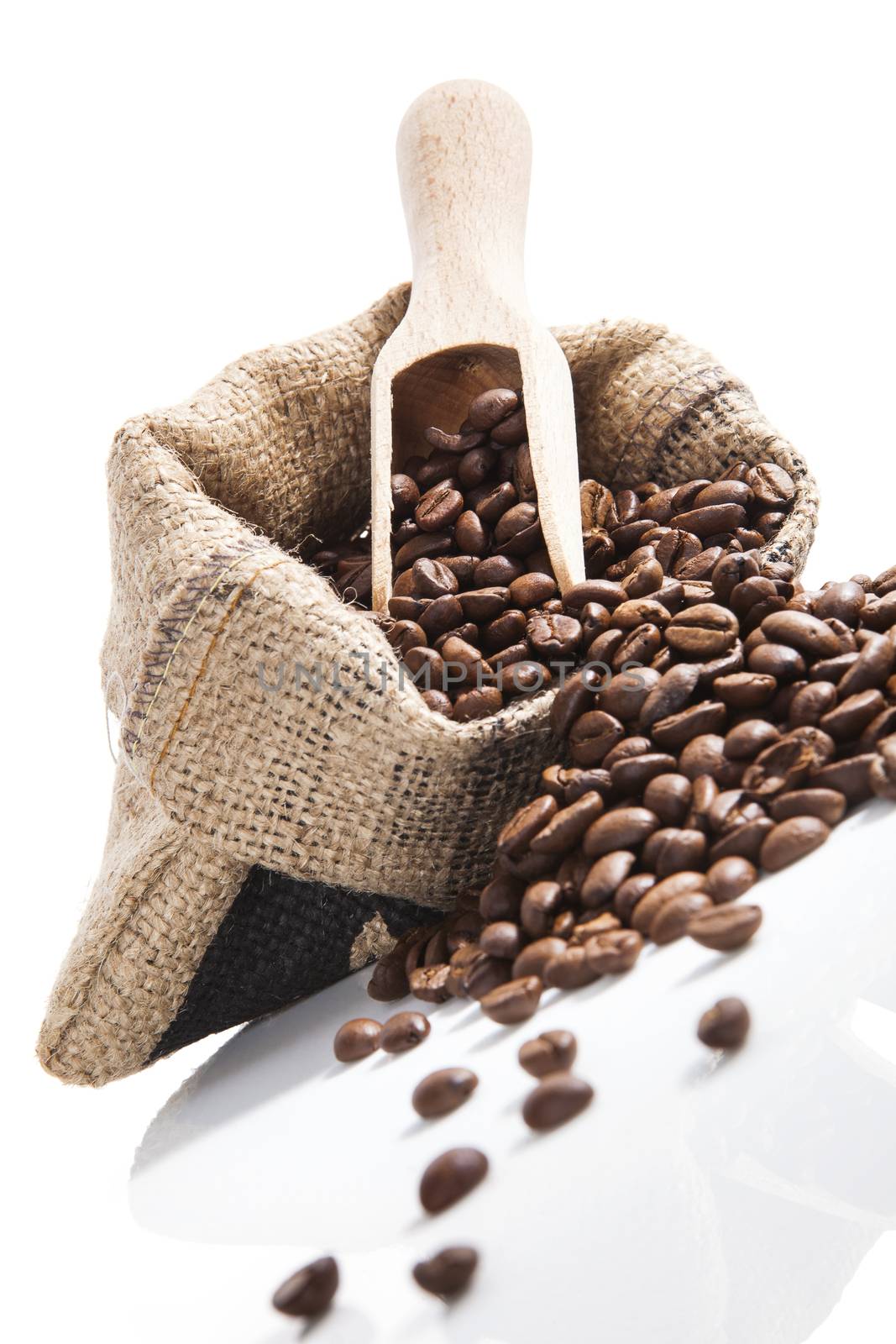 Fresh aromatic coffee beans in brown sack with wooden spoon isolated on white background. Culinary coffee drinking.