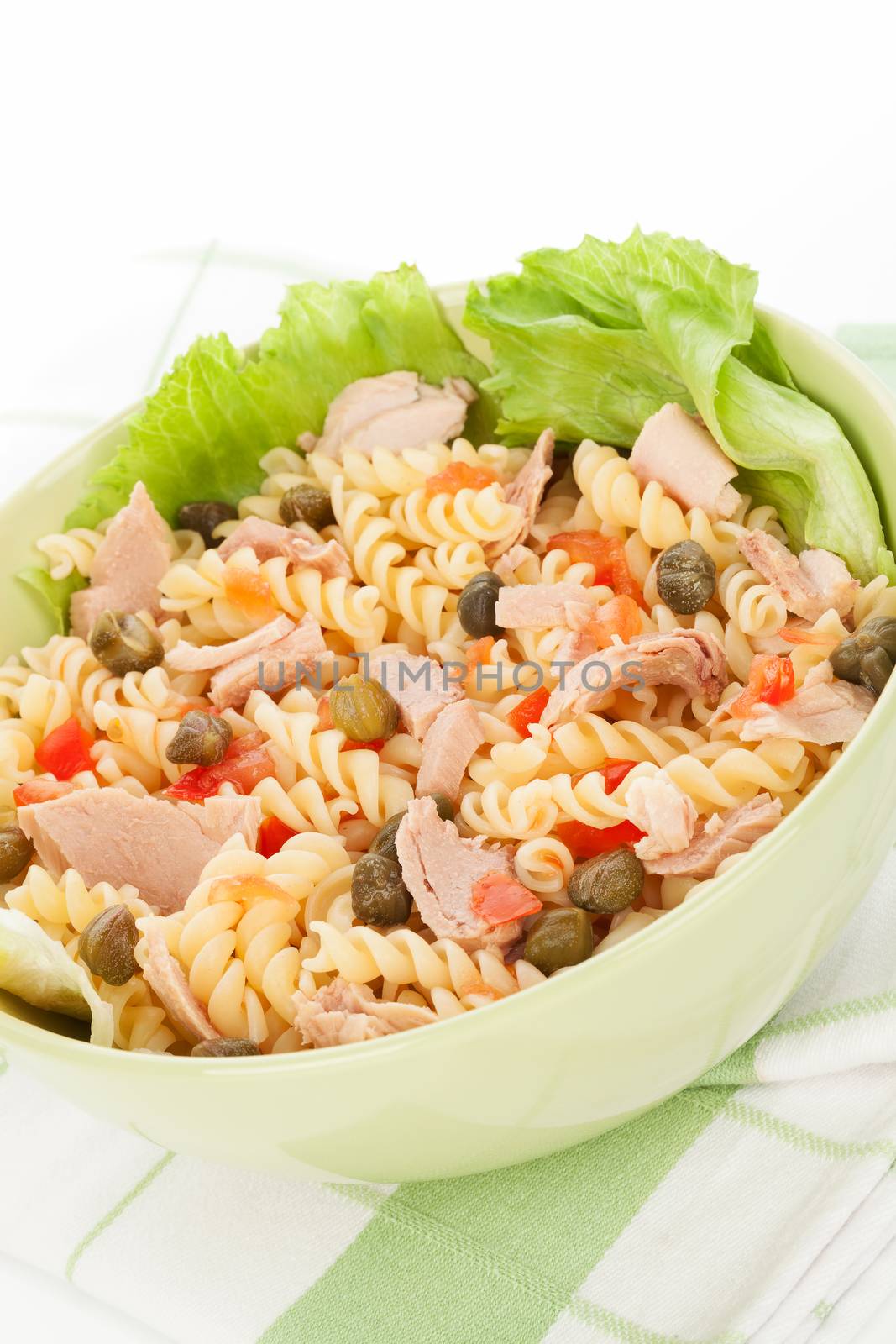 Pasta with tuna, capers, lettuce and vegetable in green bowl on white background. Culinary healthy eating. 