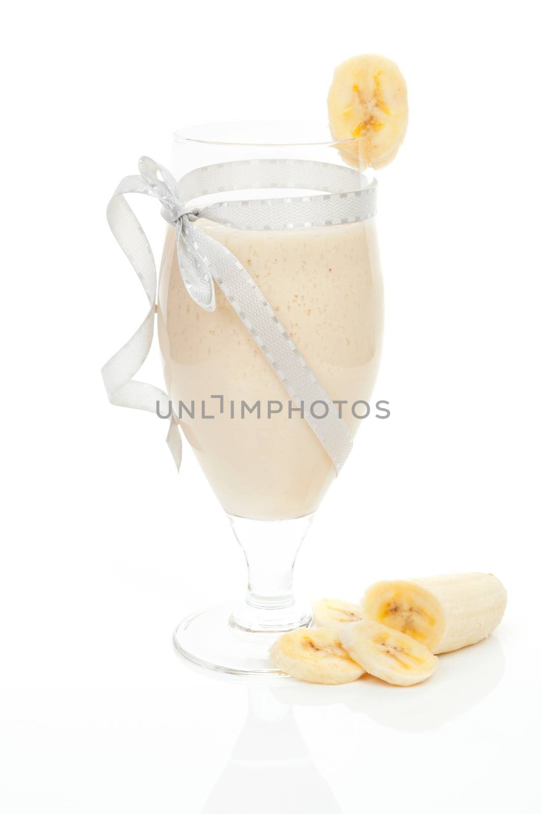 Delicious banana milkshake with cut banana isolated on white background. Fresh summer drink.