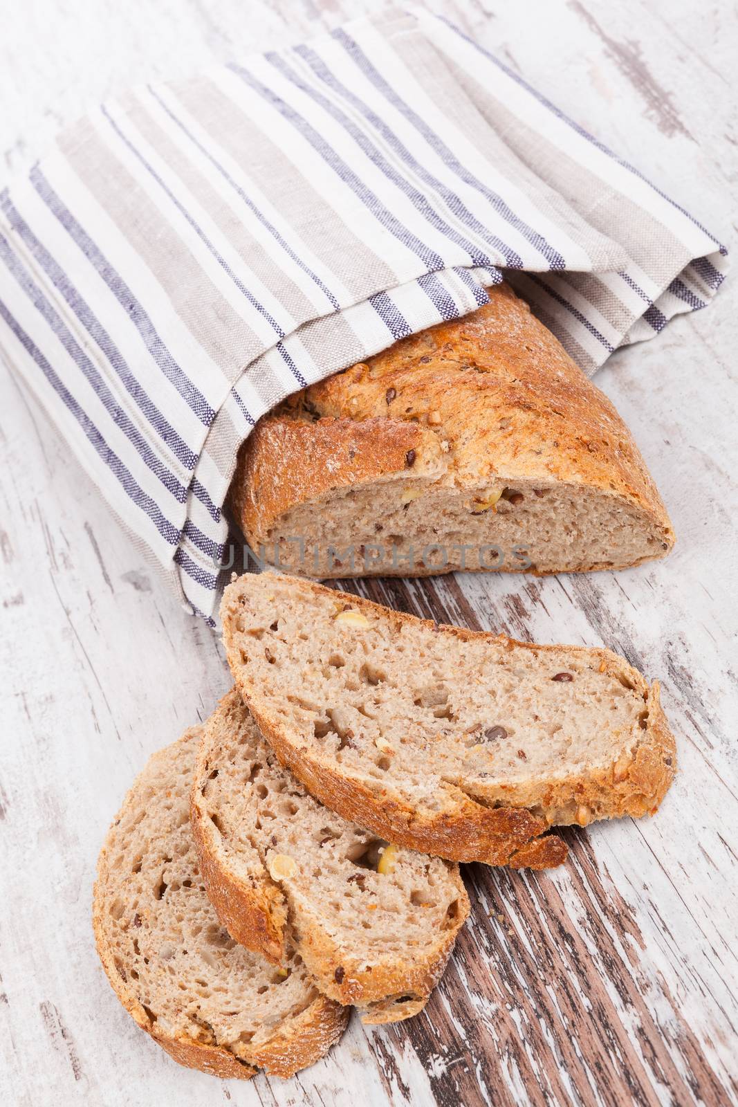 Luxurious delicious whole grain bread on white wooden textured background. Culinary healthy bread eating.