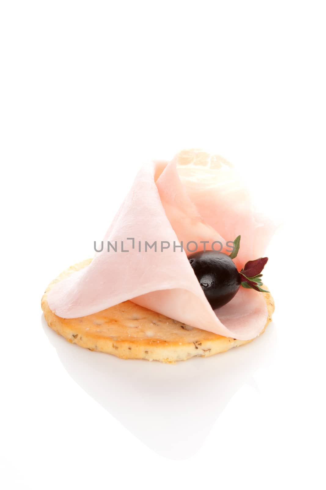 Delicious canape with ham, black olive and fresh rosemary herb isolated on white background. Culinary eating. 