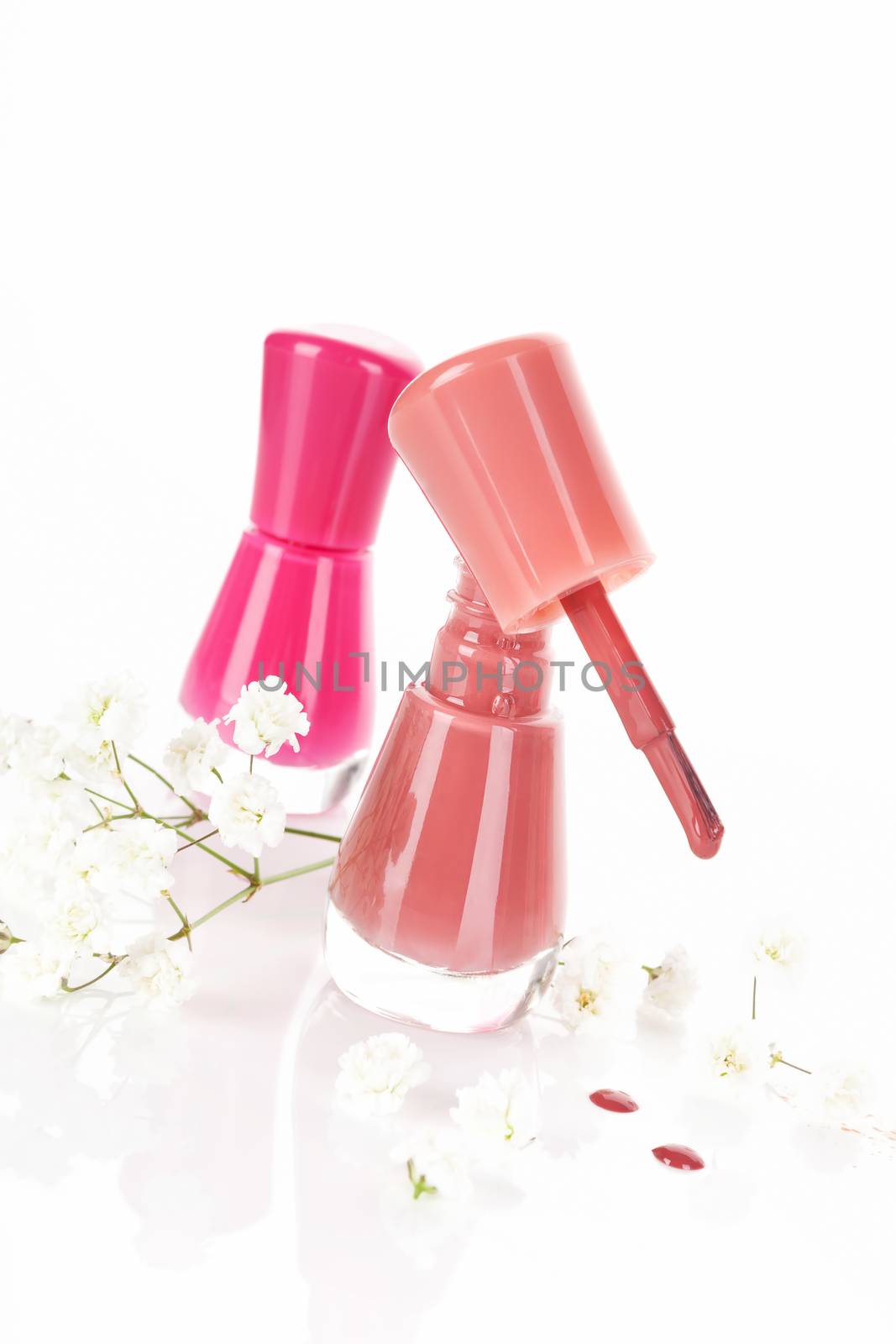 Red and pink nail polish with white flower isolated on white background with reflection. Luxurious feminine beauty background.