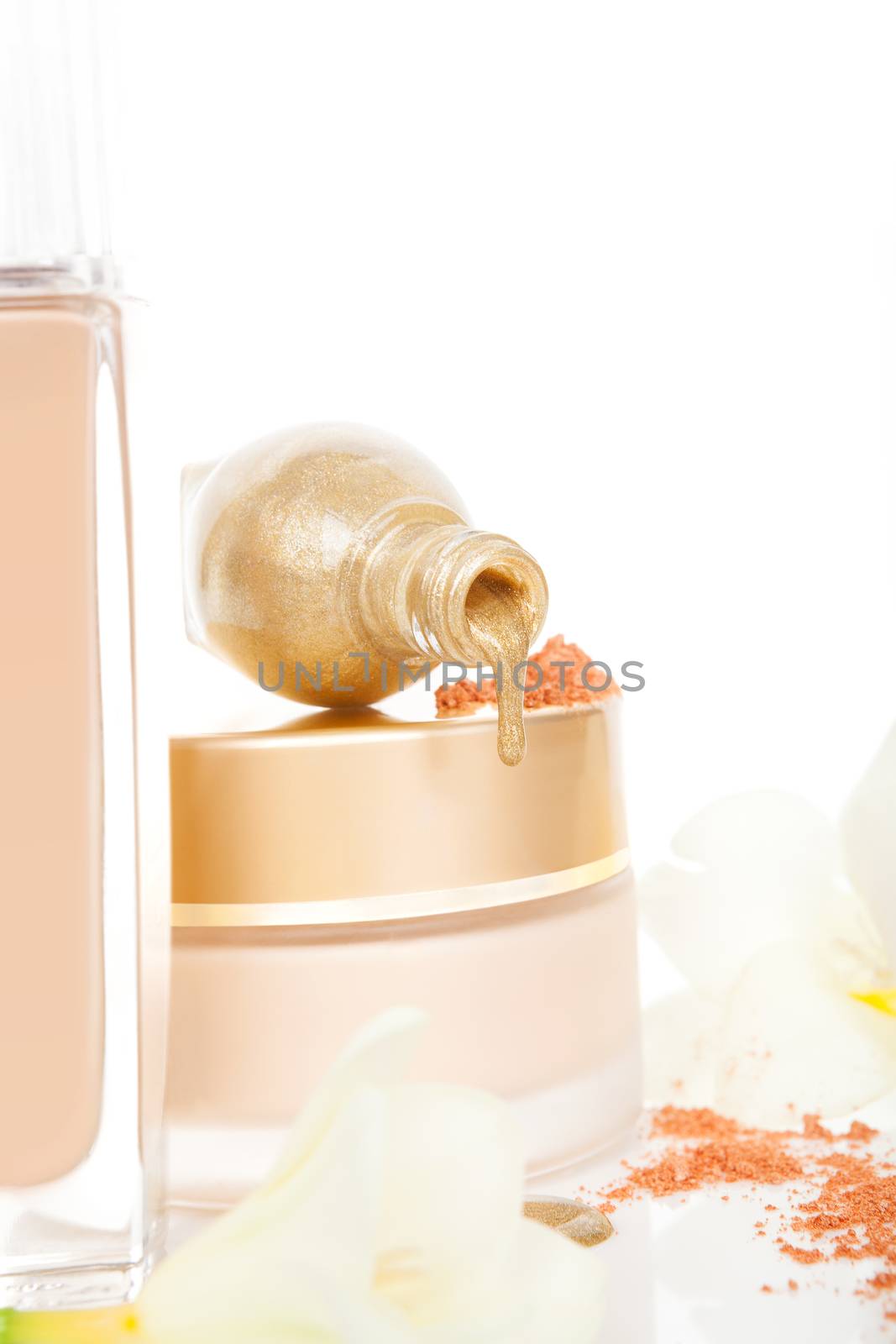 Luxurious cosmetics in beige and golden. Cream, makeup powder and golden nail polish with flower blossom isolated on white background.