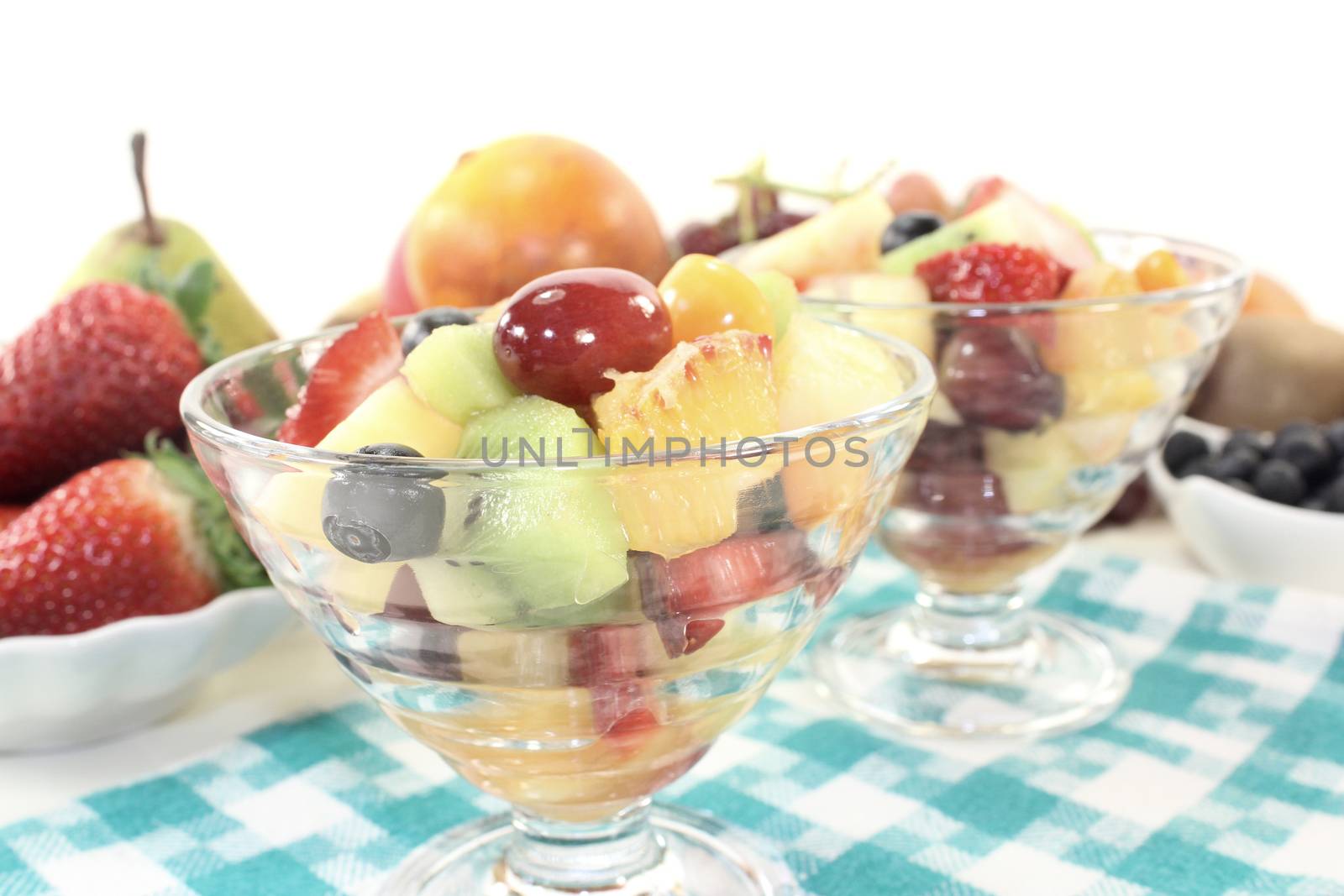 Fruit salad in a bowl on checkered napkin before light background