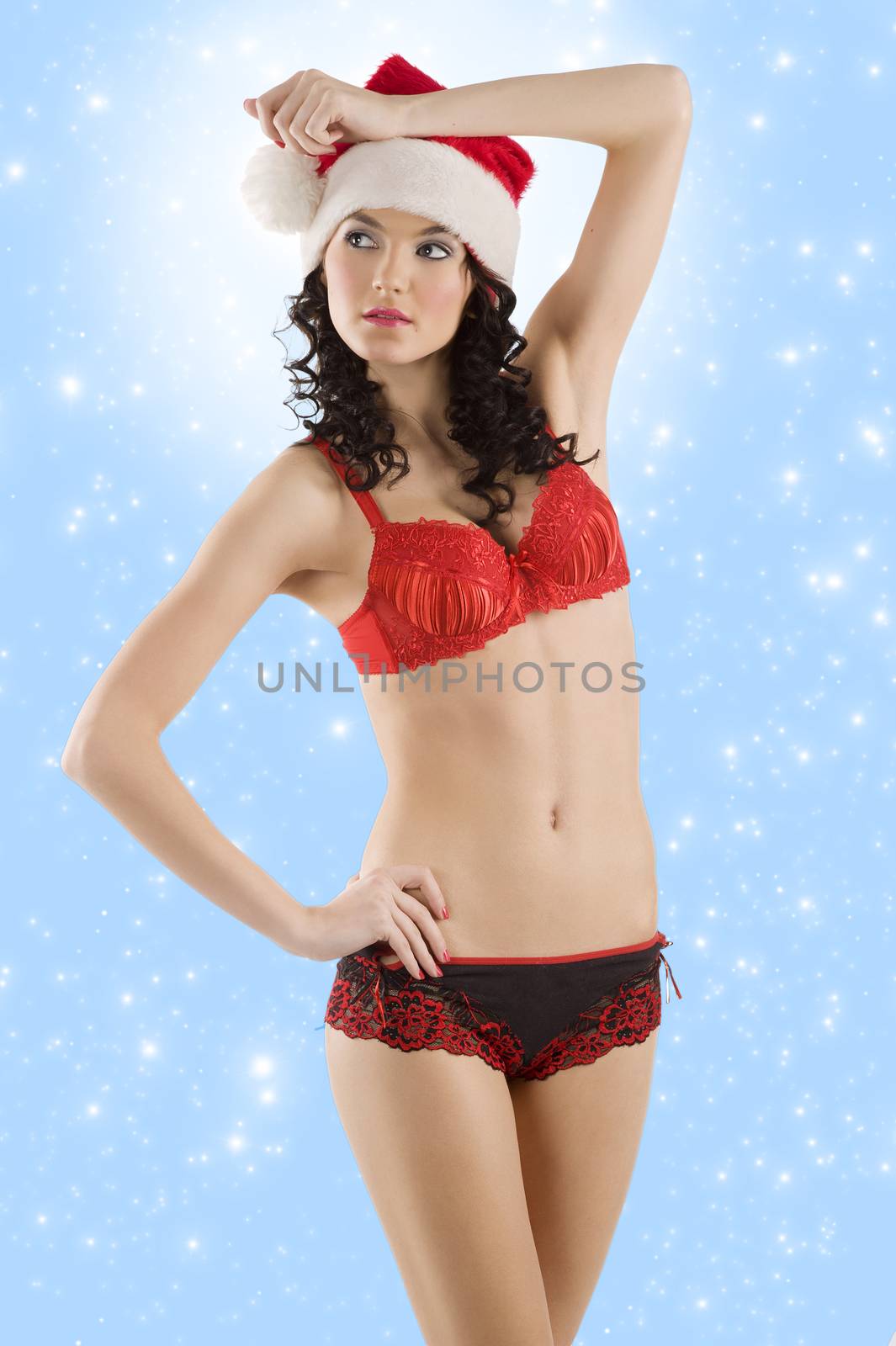 young beautiful girl wearing sexy lingerie and a christmas hat posing over white background