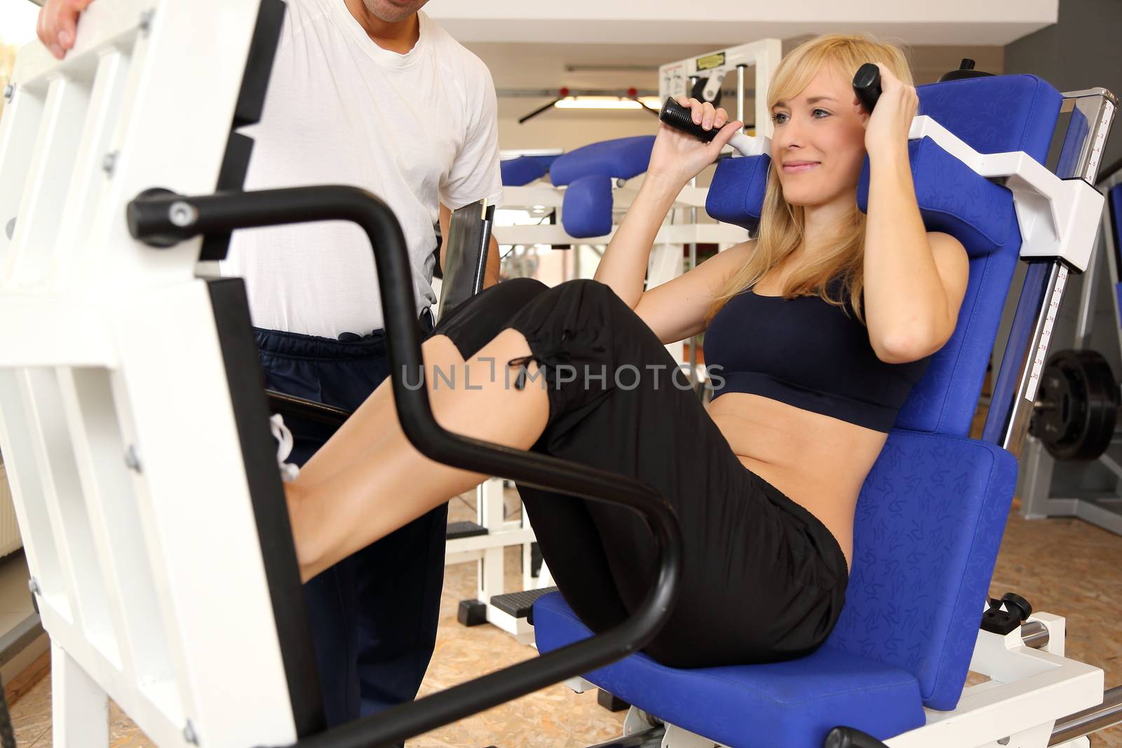 Attractive blonde woman and her trainer in a gym by ikonoklast_fotografie