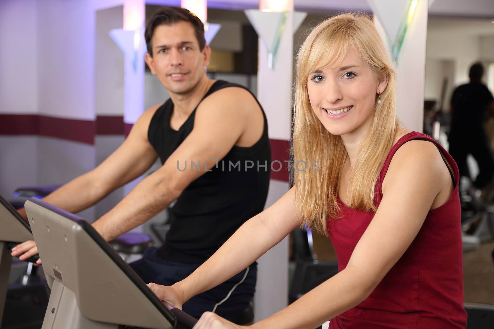 Attractive woman and a man cycling in a gym by ikonoklast_fotografie