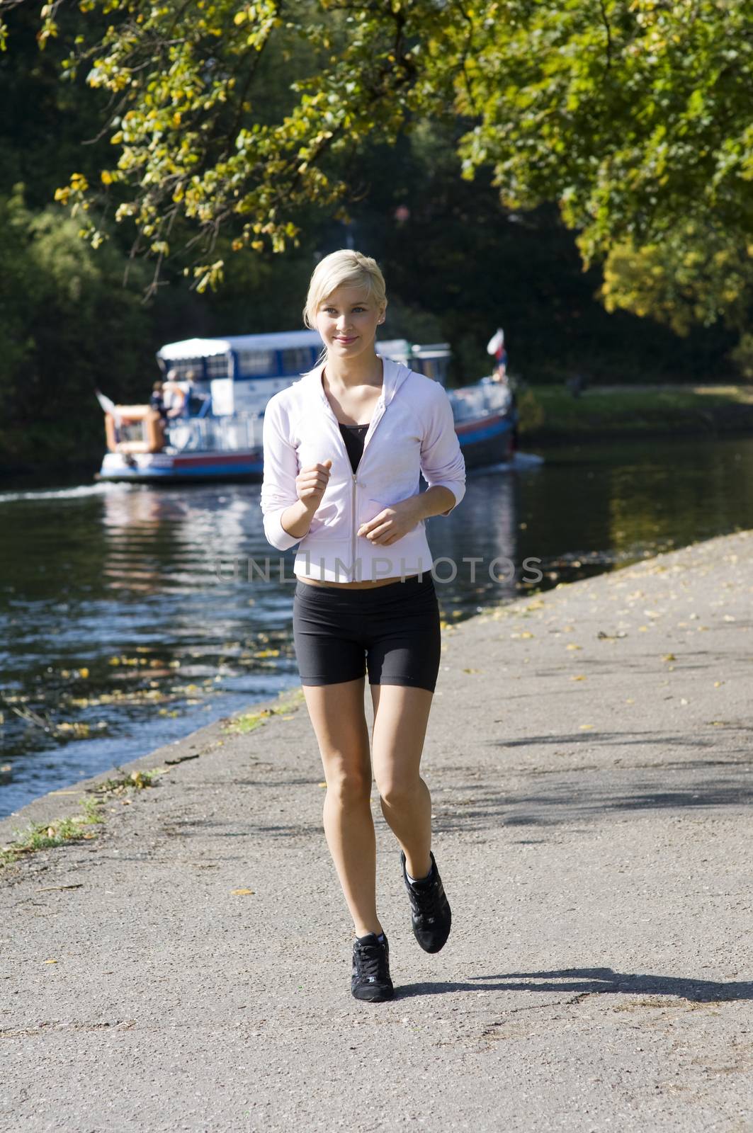 cute young girl running in the park near river the girl is a little moving