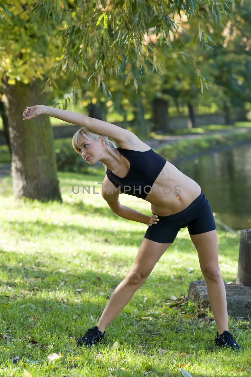 nice blond girl in black shorts making gym exercise in park