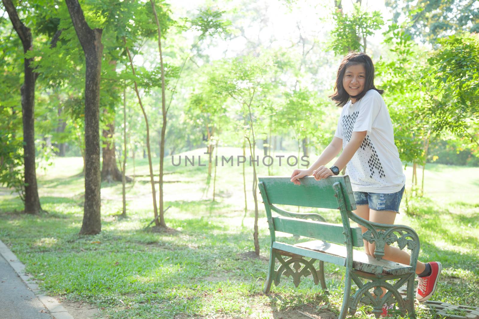 Woman standing on a stool. In the park with trees and greenery.