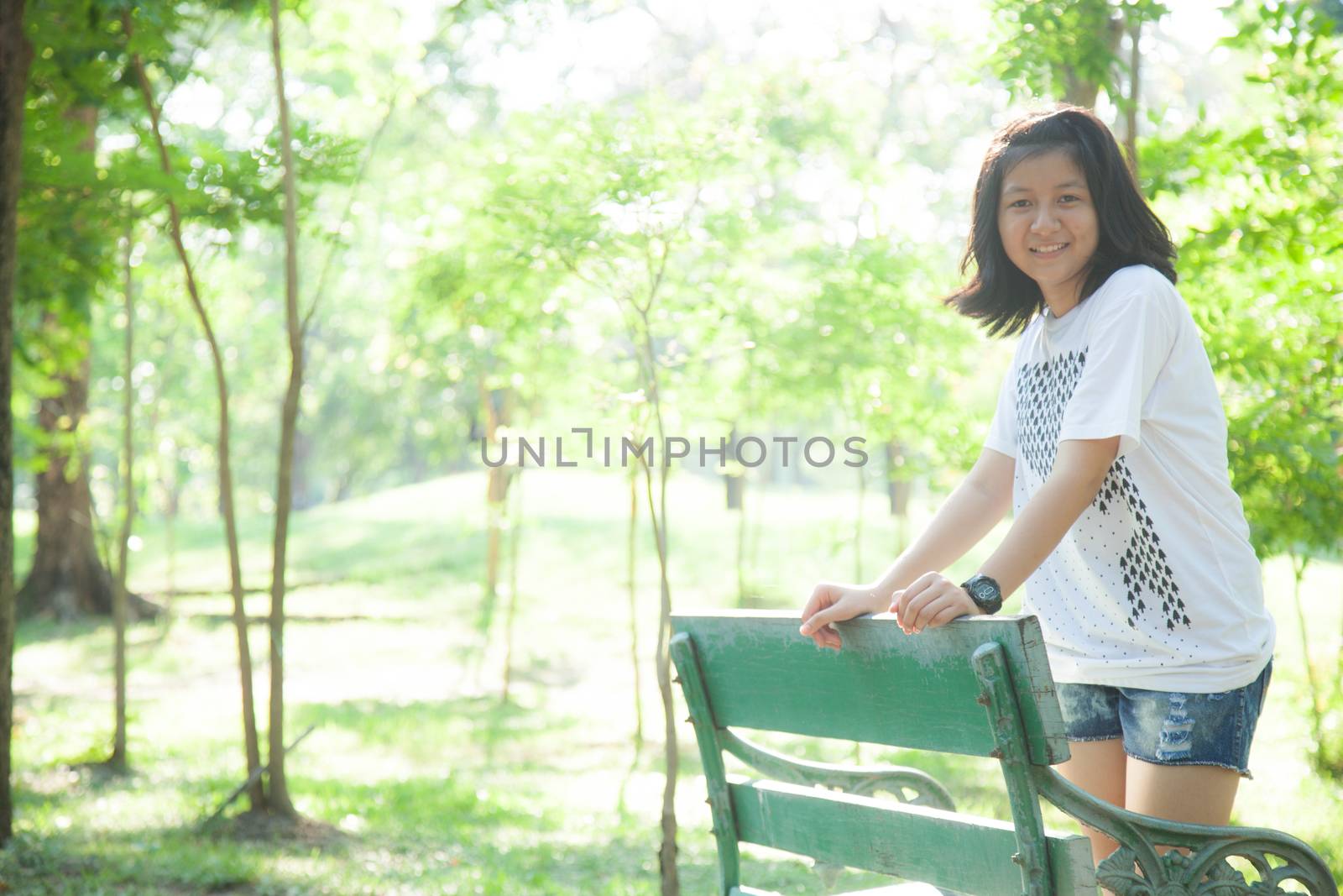 Woman standing on a stool. In the park with trees and greenery.