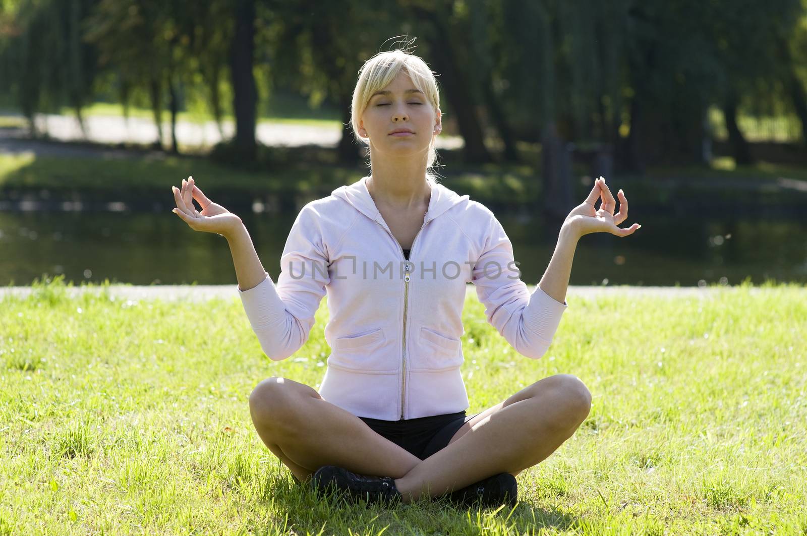 young and beautiful woman in a classical yoga pose outdoor in park