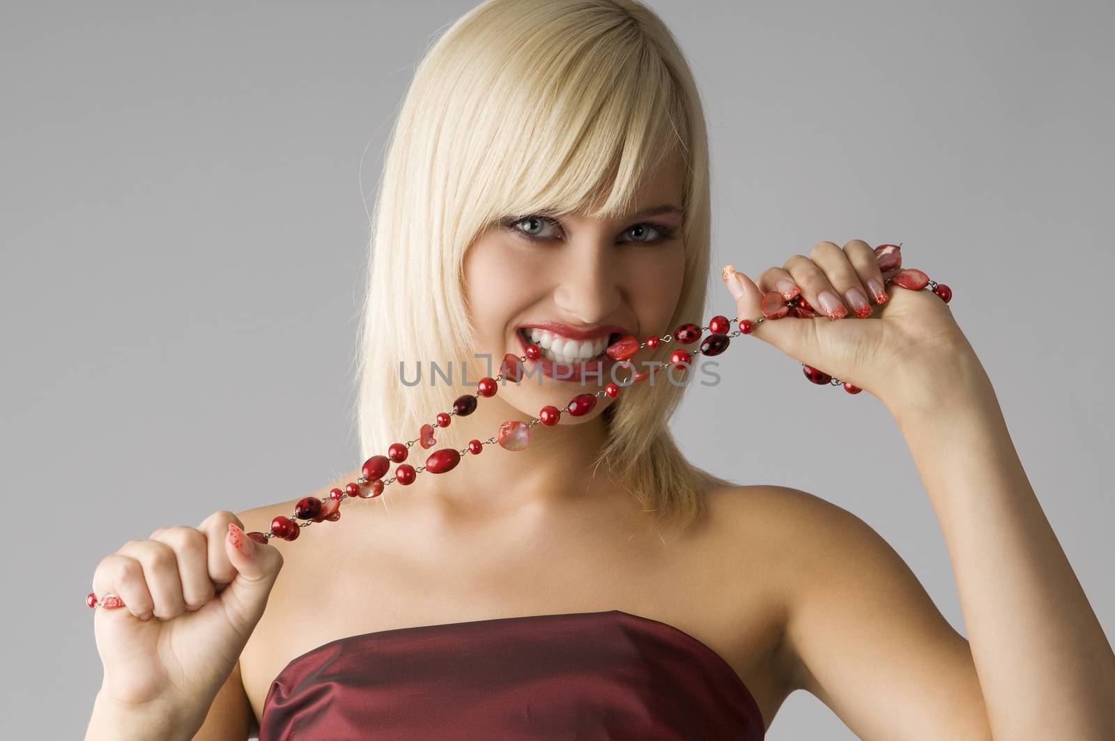 cute blond girl with glamor make up biting a red necklace