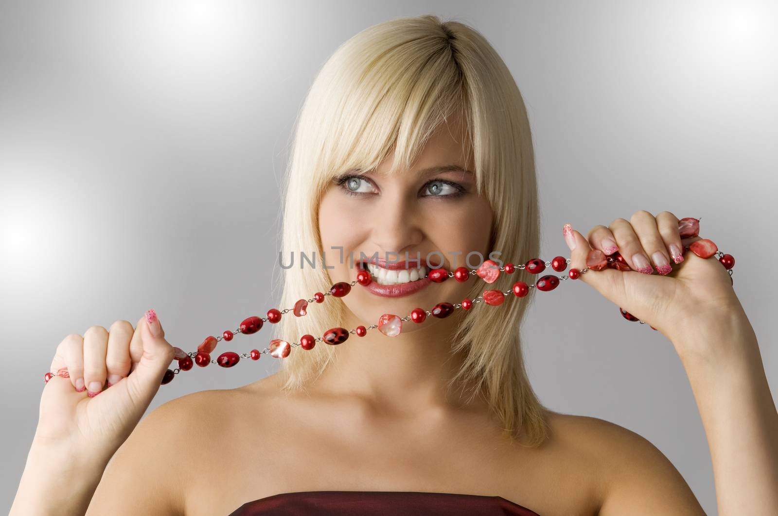 cute blond girl with glamor make up biting a red necklace