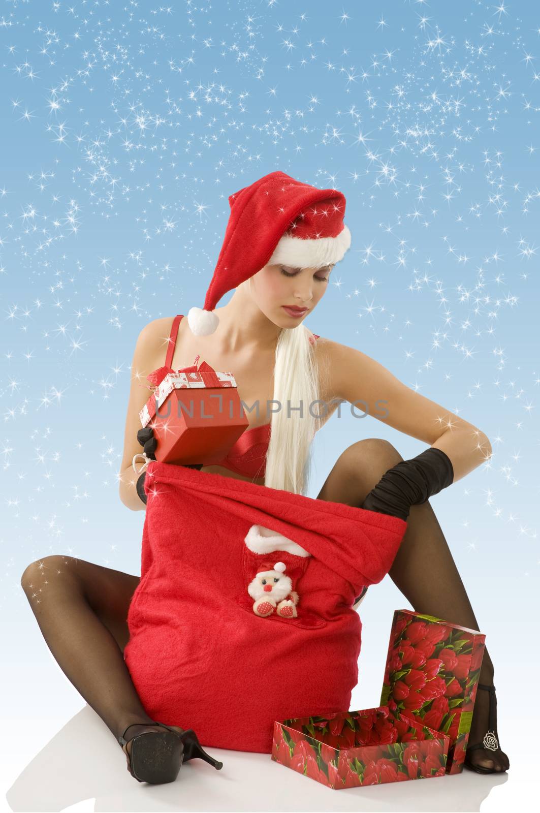 beautiful sexy blond santa claus sitting on floor looking inside her gift sack