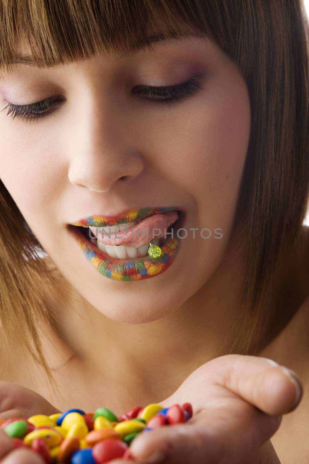 young pretty girl with colored smarties in hand making face