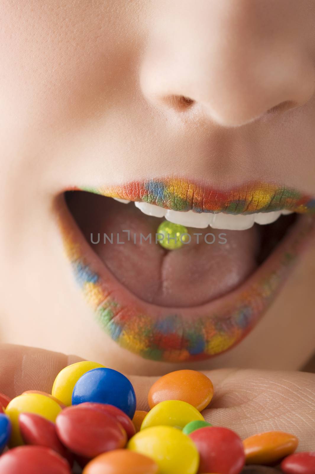 close up of a mouth with multicolor lips and colored smarties
