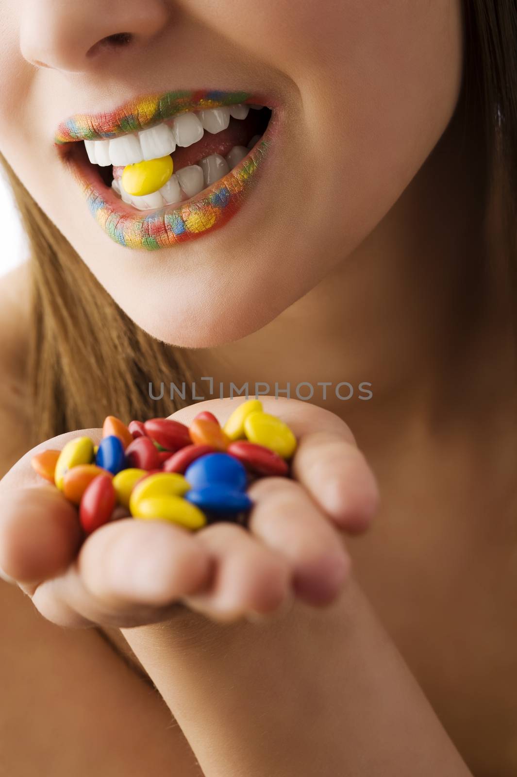 close up on a mouth multicolor keeping a smarty between teeth