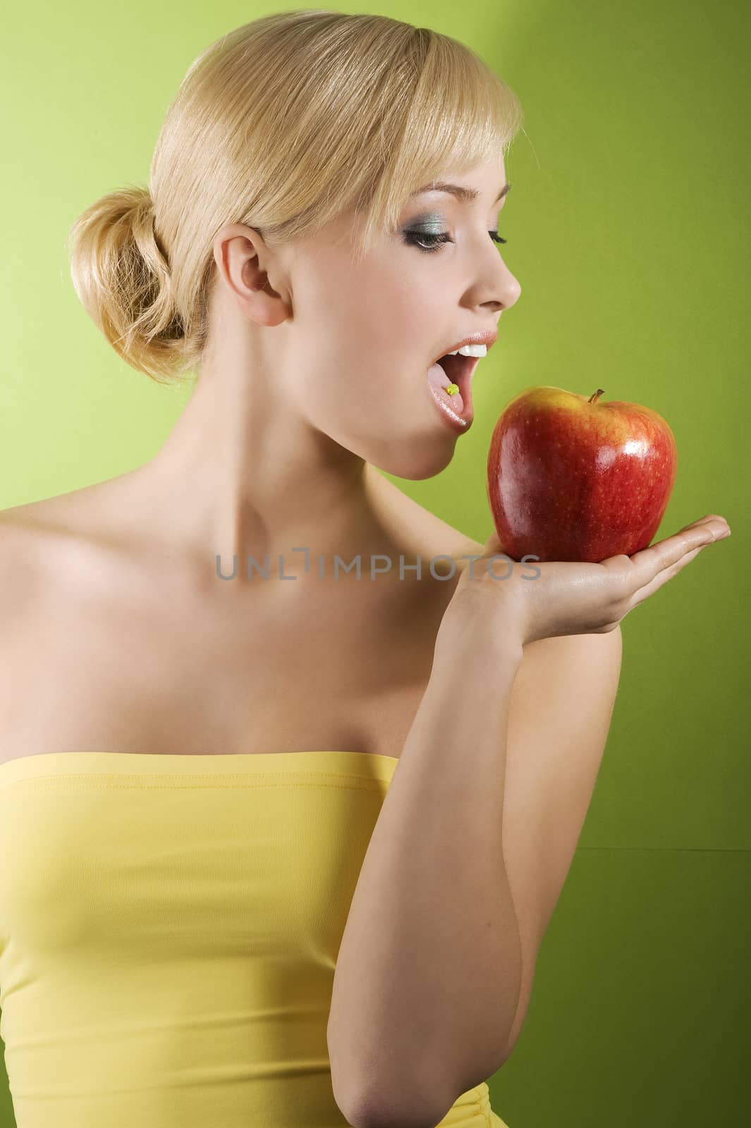 nice shot of a young beautiful woman on colored background in act to eat a red apple