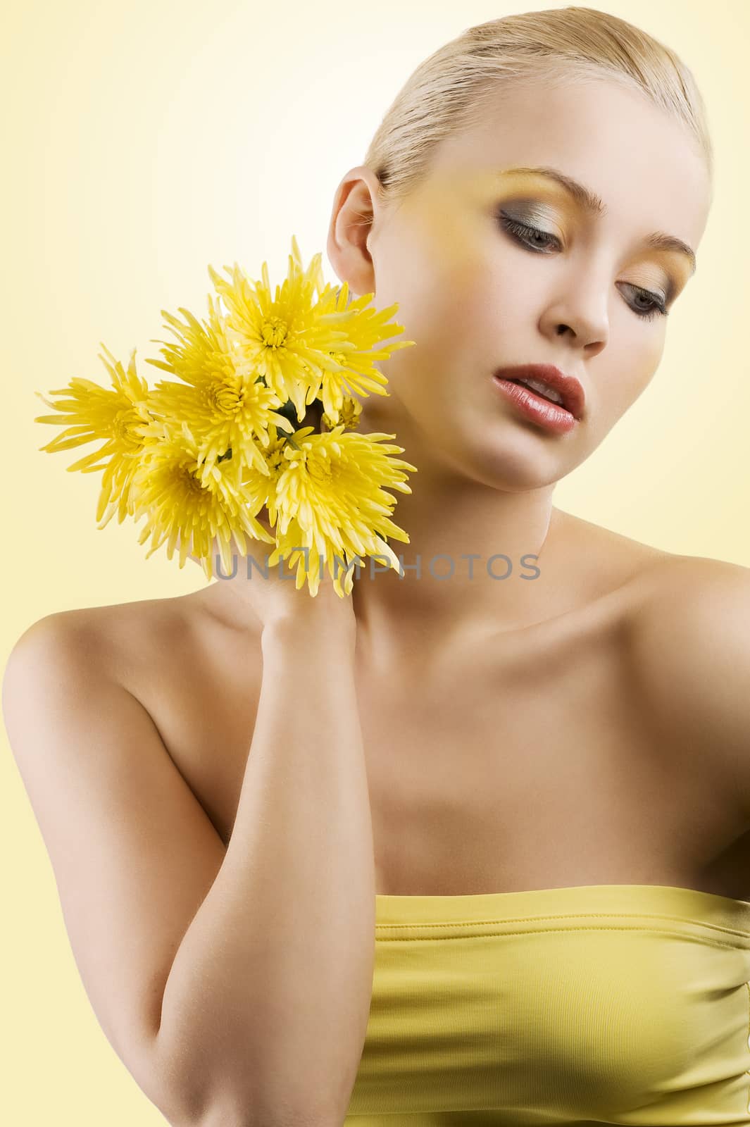 sweet and beauty blond girl wearing a yellow top keeping yellow flower and looking down. wellness concept