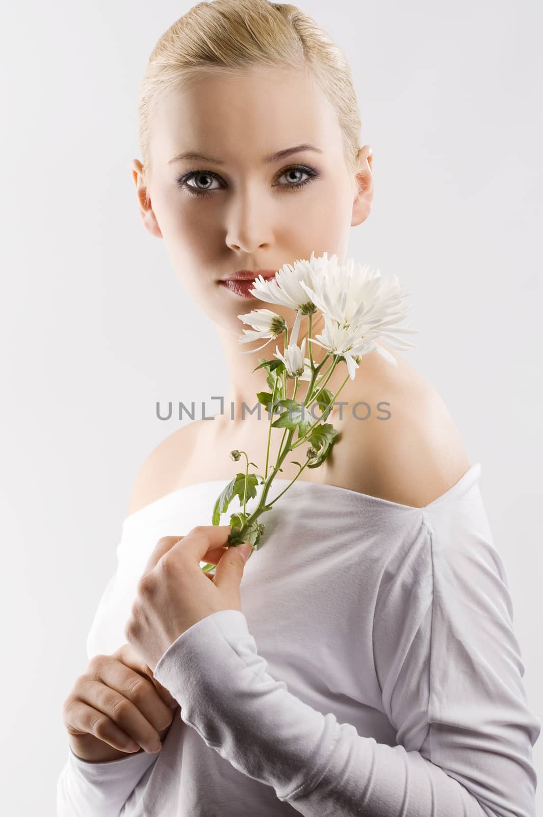 beauty portrait of young cute blond girl with white top and some flowers near face