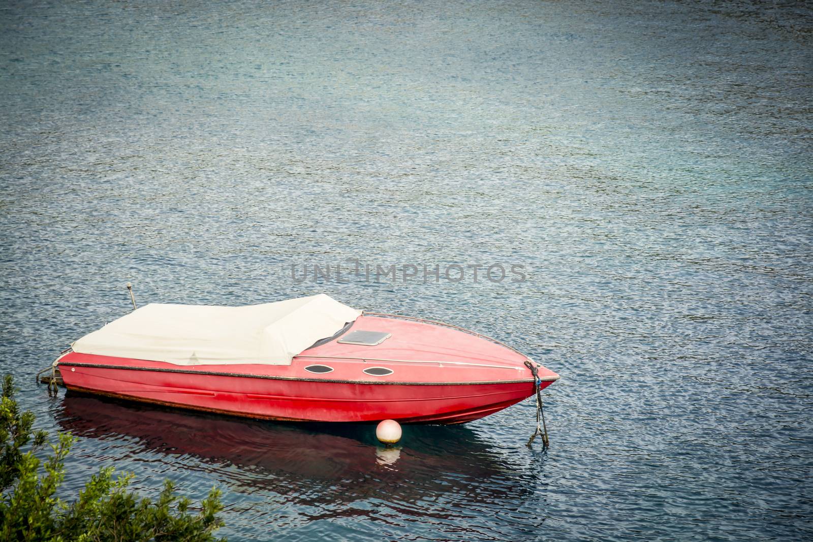Red speed motor boat moored and with white boatcovers on in Mediterraanean water, Mallorca, Balearic islands, Spain.