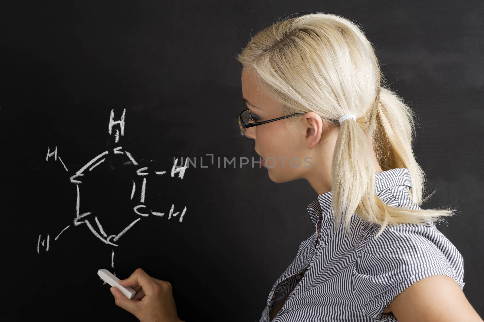 pretty young college student writing on the chalkboard/blackboard during a math class