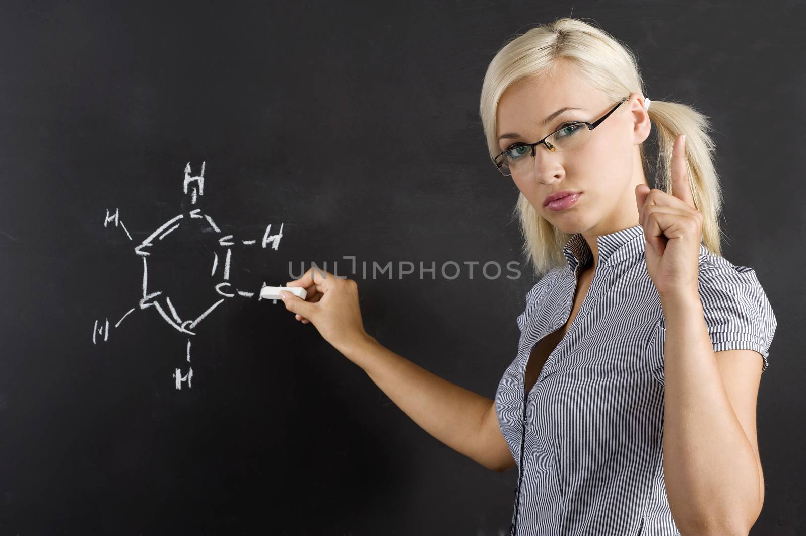 very pretty and young teacher in act to take a lesson near a blackboard