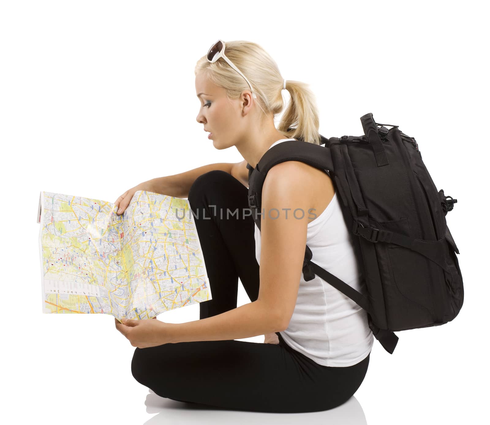 young pretty student girl in vacation sitting down and looking for place on a map